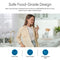 A smiling woman stands in a bright kitchen, holding a glass of water. The Curvy Classic Series Water Faucet in Brushed Gold features lead-free 304 stainless steel, food-grade materials, and is ideal for water filtration systems.