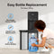 A woman kneels, sliding a large water bottle into the Bottom Load Bullet Ice & Hot/Cold Water Dispenser – Model 320 Ice, featuring a sleek black finish. Text highlights easy bottle replacement, no heavy lifting required, and compatibility with both 3- and 5-gallon bottles.