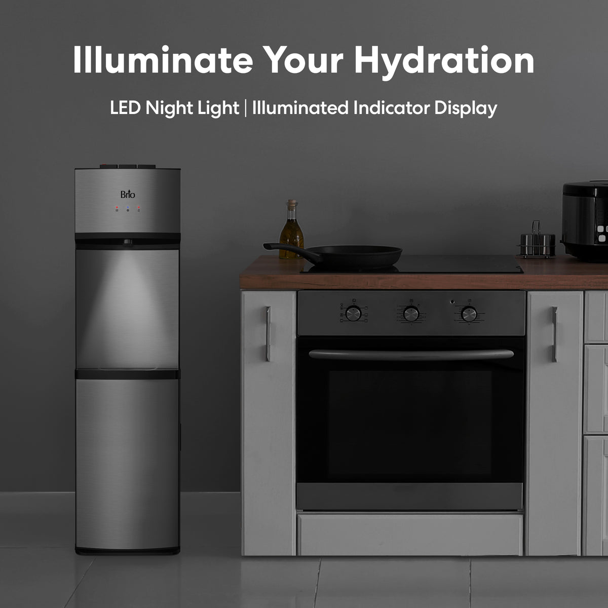 A Stainless Steel Bottom Load Water Dispenser - Model 530 BL with LED indicators stands beside a modern kitchen oven and countertop with various kitchen items. Text above reads: Illuminate Your Hydration, highlighting the self-cleaning technology and LED night light features.