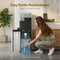 A woman kneels to slide a large water bottle into the bottom compartment of the Coffee Maker & Bottom Load Water Cooler Dispenser - Moderna Series, demonstrating easy bottle replacement. Text above reads: Easy Bottle Replacement. Slides in, no heavy lifting.