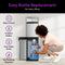 A woman kneels to slide a 5-gallon water jug into the open compartment of the Bottom Load Water Dispenser - Model 740. The dispenser door is open, while highlighted text calls out features such as easy bottle replacement, tri-temperature dispensing, and self-cleaning UV technology with no plumbing needed.