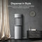 A 3-Stage Bottleless Water Dispenser - Moderna 730 stands in a stylish room with gray walls, a clock, a cabinet, and beige curtains. Text above highlights its sleek stainless steel design, premium features, and advanced 3-stage filtration system for exceptionally pure water.