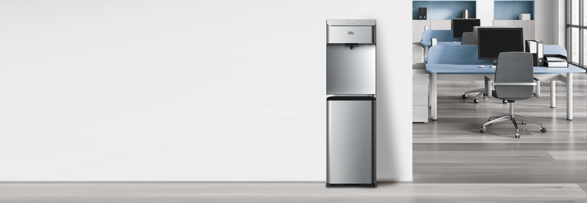 A stainless steel water cooler stands against a white wall in a modern office with blue desks, black chairs, and computers visible in the background.