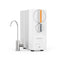 A sleek, modern white SIMPL Series Tankless Reverse Osmosis Under Sink Filtration System 600GPD by Brio, featuring a silver faucet. This unit includes two round front control dials with indicator lights and delivers advanced 600 GPD filtration for outstanding water quality.