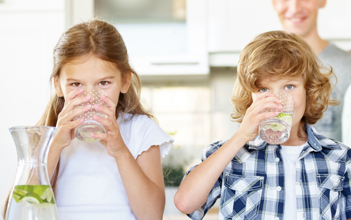 A girl and boy drinking glasses of water