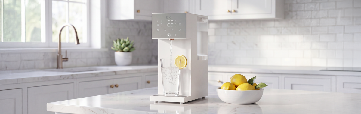 Brio SIMPL W3 countertop water dispenser dispensing filtered water into a glass with lemon on a modern kitchen countertop.