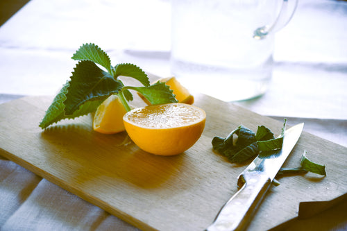 a wooden chopping board with lemons, mint and chopped herbs