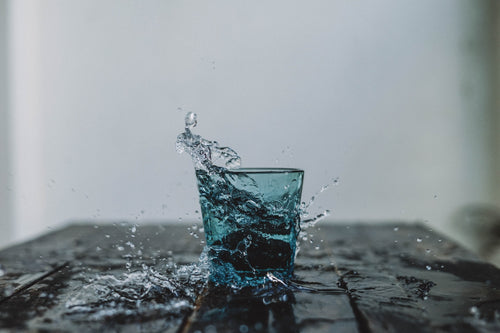 blue glass on a wooden table filled to overflowing with filtered water 