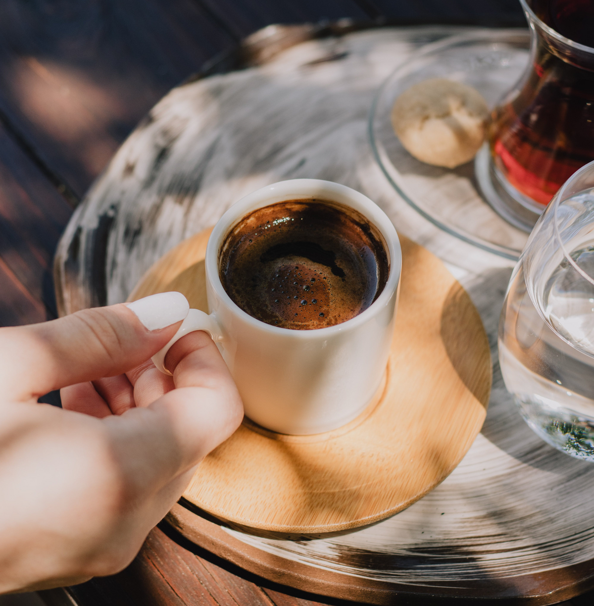 A woman holding a fresh cup of black coffee