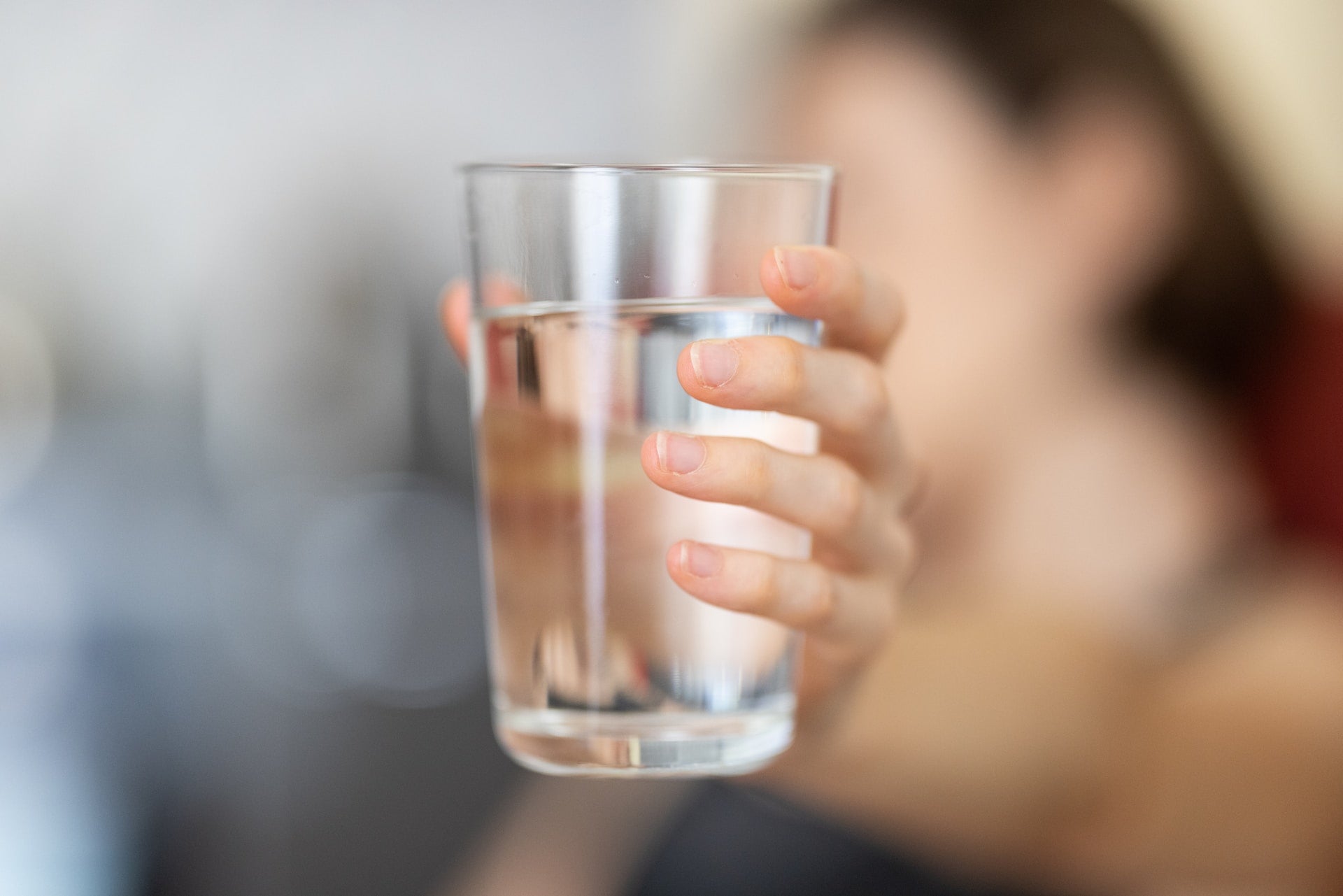 woman holding out a glass of filtered water