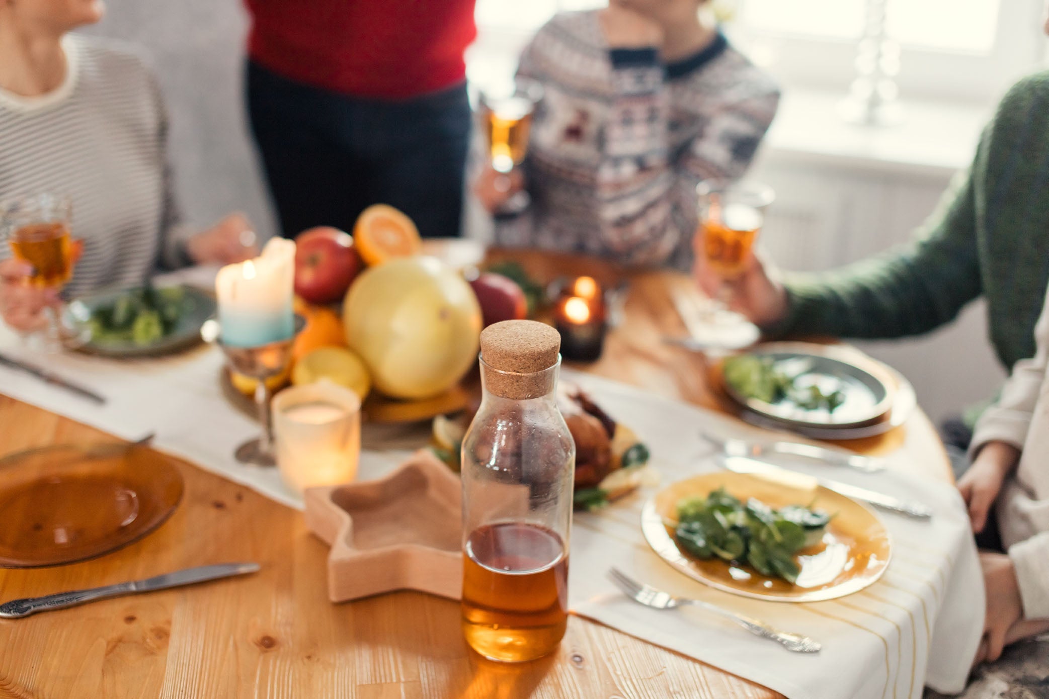 A group sitting around a dinner table celebrating the holidays with drinks