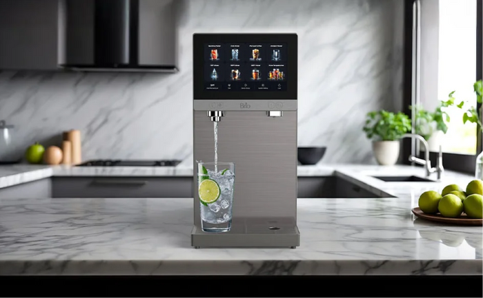 Brio Q60 smart water dispenser on a marble countertop, featuring a touchscreen display and dispensing sparkling water with lime slices.