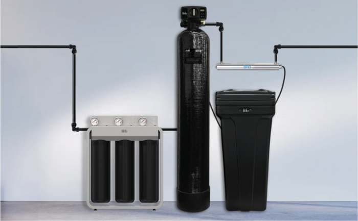 Brio whole house three-stage water filtration and softener system with brine tank, and UV sterilization pipe installed along a wall with black tubing.