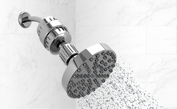 Brio chrome shower filter with running water spray in a modern white tiled bathroom.