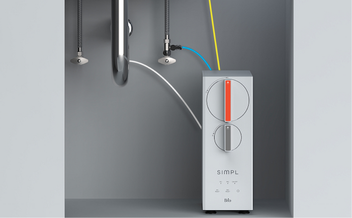 Brio SIMPL undersink water filtration system with connected tubing and dual control dials installed below a kitchen sink.
