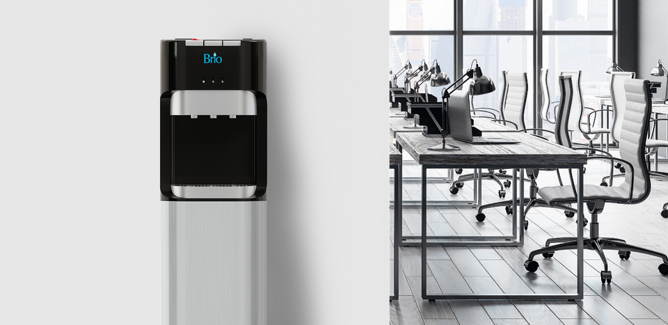 A modern water dispenser is mounted on a wall next to a bright, spacious office with rows of desks, chairs, computers, and large windows overlooking a cityscape.