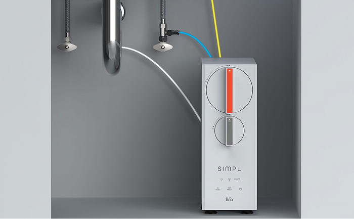Brio SIMPL undersink water filtration system installed beneath a kitchen sink, featuring sleek dials and connected water lines.