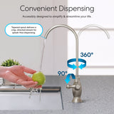 A hand washes a green apple under the Brio Curvy Classic Series Water Faucet – Brushed Nickel, a lead-free stainless steel faucet with 360° and 90° rotation for splash-free, directed flow—ideal for reverse osmosis setups and convenient dispensing.