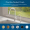 A Modern Series Water Faucet - Chrome is installed on a white countertop near a window. Six circular swatches below show available finishes: brushed gold, brushed bronze, brushed nickel, chrome, matte black, and white.