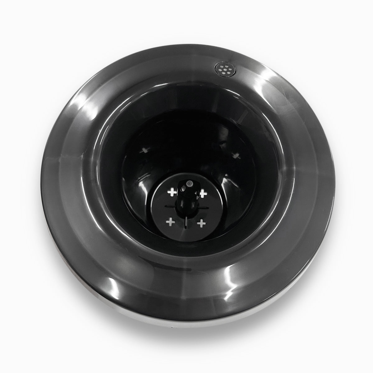 A top-down view of a shiny stainless steel Non-Spill Top 420, 520 Coolers base with a dark central blade and visible plus and minus symbols, set against a white background.