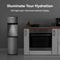 A Stainless Steel Bottom Load Water Dispenser - Model 530 BL with LED indicators stands beside a modern kitchen oven and countertop with various kitchen items. Text above reads: Illuminate Your Hydration, highlighting the self-cleaning technology and LED night light features.