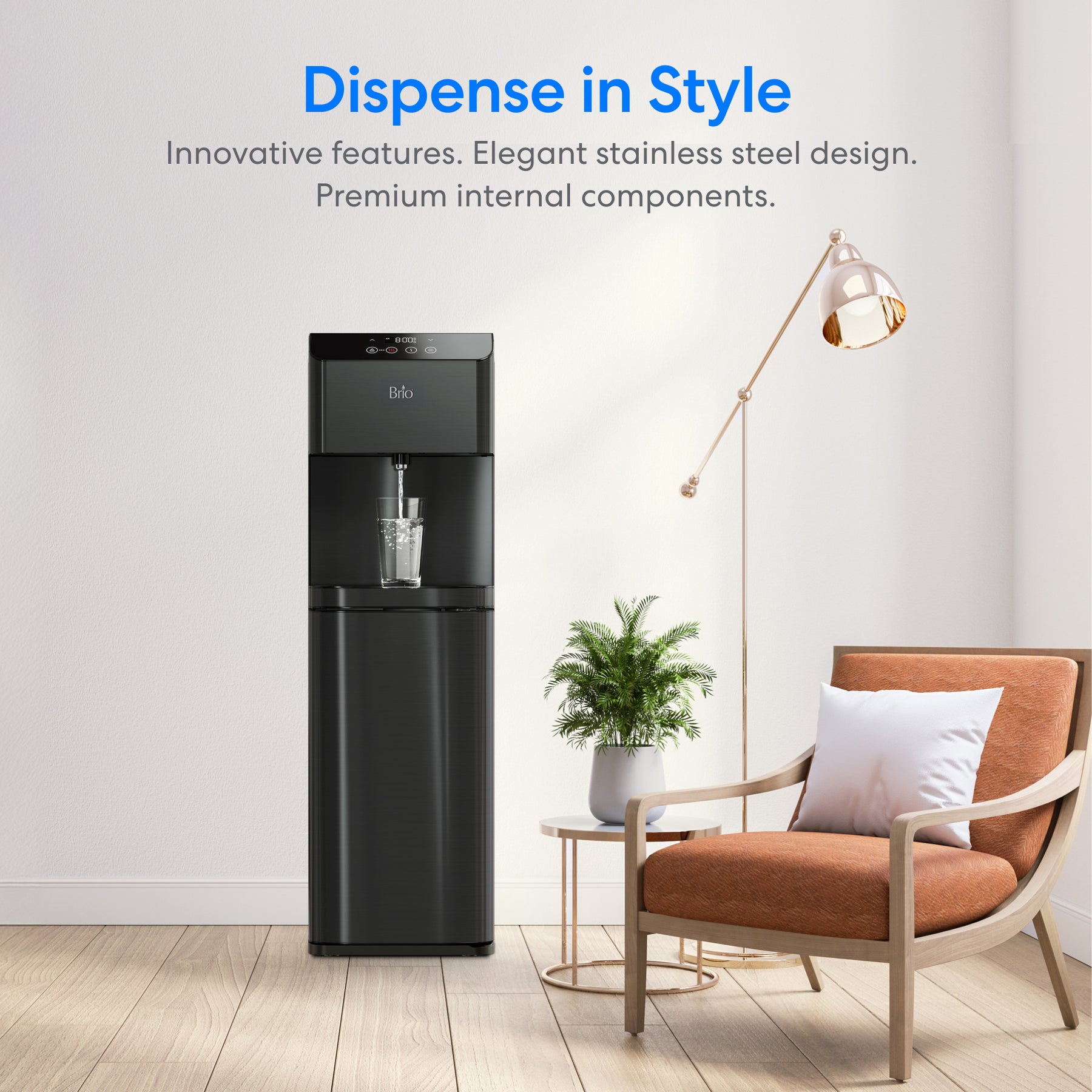 The Brio Moderna Self-Cleaning Black Stainless Bottom Load Water Cooler stands by a white wall in a modern room with a floor lamp, potted plant, and armchair with white and light brown pillows. Blue text above reads, Dispense in Style.