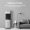 A modern living room featuring the Stainless Steel Ultrafiltration Bottleless Water Dispenser - Model 520, a black floor lamp, a gray couch, and a small decor table beneath text highlighting the stylish features of this water dispenser.