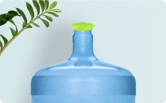 Large blue water jug with a bright green cap, positioned beside a leafy plant against a light background.