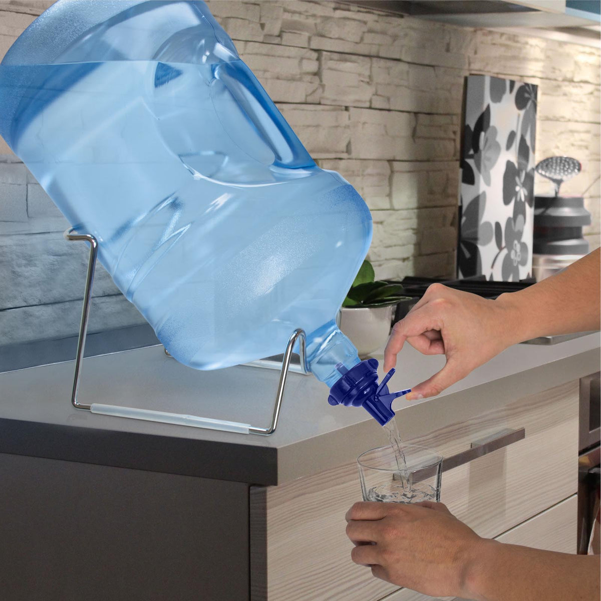A person uses the 48MM Dark Blue Screw Top Valve Display Package on a water jug with a spout on a metal stand to fill a glass in a modern kitchen.