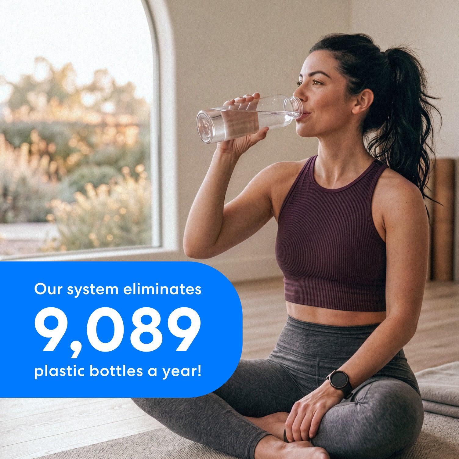 Image of a woman in workout clothing sitting on the floor drinking water to illustrate that the Brio 16″ Premium Under Sink Filter PFAS-Reduction System with stainless steel faucet eliminates up to 9089 plastic bottles in one year.