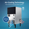 The Monarch 80 Lb Capacity Ice Machine with 33 Lb Storage Bin features air-cooling technology, using ambient air to boost system longevity and save on operating costs. Blue and red arrows highlight airflow, while black legs support its stainless steel body.
