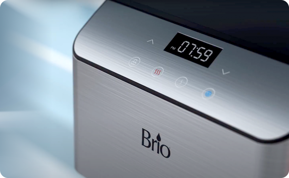 Close-up of a Brio appliance with a digital display showing the time “07:59 PM” and touch buttons for various settings on a brushed metal surface.