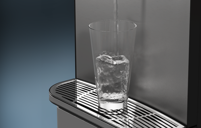 Close-up of a clear glass filled with ice being placed under a water dispenser, with water pouring into the glass against a metallic background.
