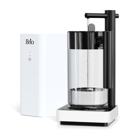 The Brio Amphora RO Undersink Filtration System - Pitcher features a modern clear cylindrical pitcher with a black and white base, tall black automatic spout, and a separate white rectangular unit with the Brio logo for advanced water filtration.