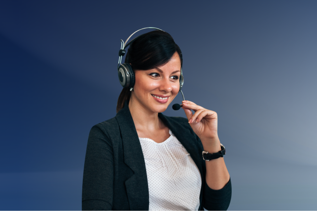 A woman wearing a headset and microphone smiles while sitting against a blue background, appearing to provide customer support or participate in a call.