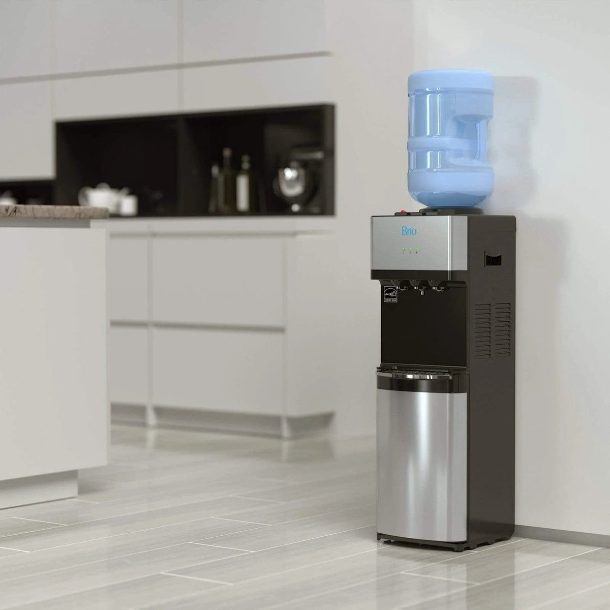 A Stainless Top Load Water Cooler - 520 Series with a blue water jug stands against the wall in a sleek, minimalist kitchen featuring light cabinets and a tiled floor.
