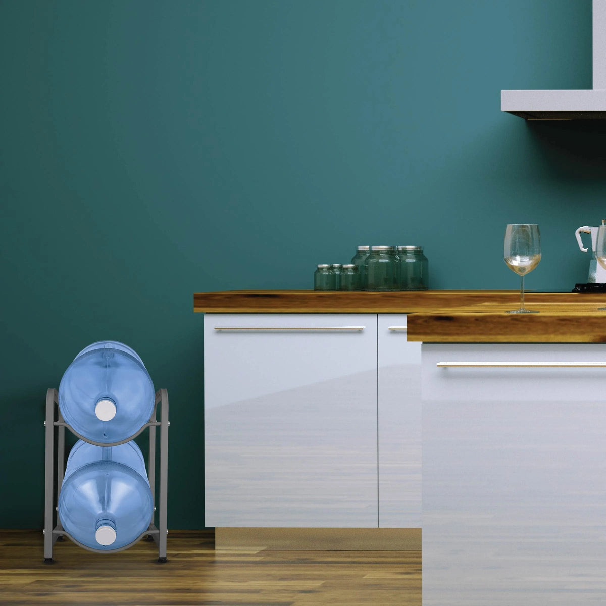A modern kitchen with white cabinets, a wooden countertop, the gray Single Column 2-Bottle Storage Rack holding two large blue water jugs, glass jars, a blender, and a wine glass on the counter against a teal wall.