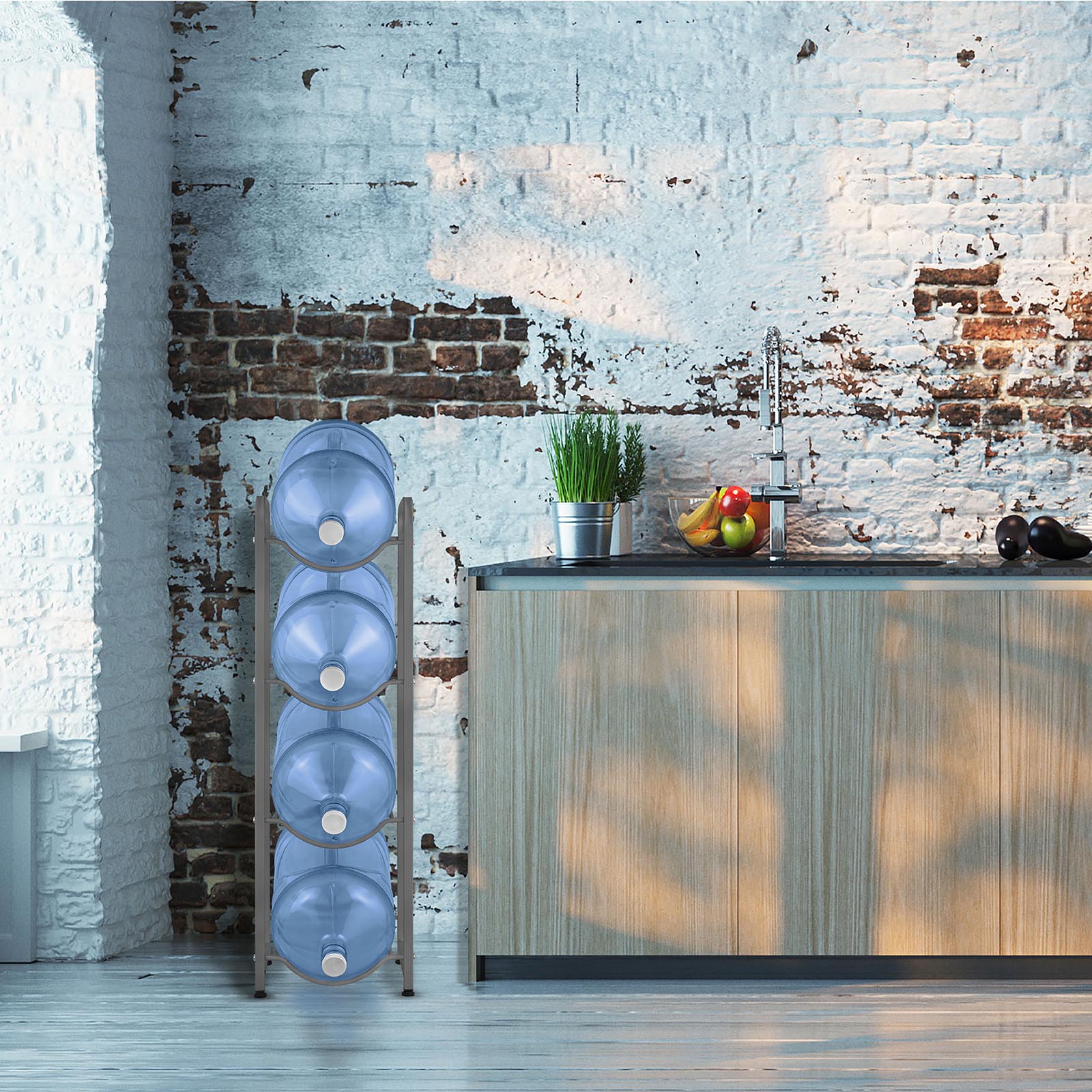 A modern kitchen features a rustic white and brick wall, wooden cabinets, and a countertop with fruit bowl and potted plants. To the left, the Brio Single Column 4-Bottle Storage Rack - Gray neatly stores four large water jugs for efficiency.